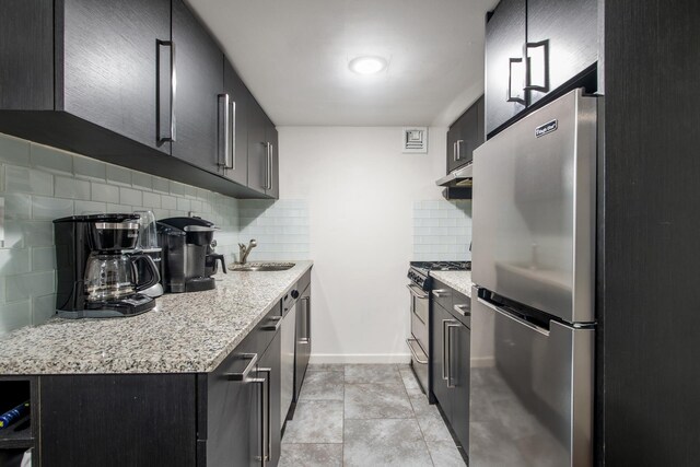 kitchen with tasteful backsplash, sink, light tile patterned flooring, stainless steel appliances, and light stone counters