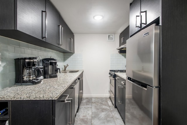 kitchen with tasteful backsplash, under cabinet range hood, light tile patterned floors, appliances with stainless steel finishes, and a sink