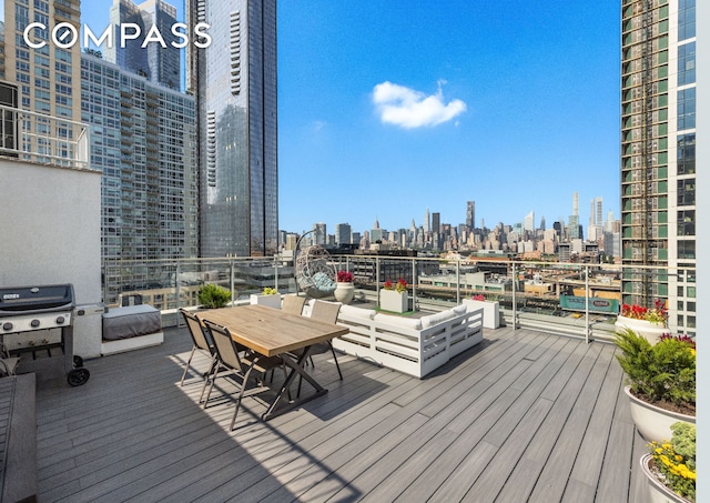 wooden terrace with outdoor dining space, a grill, and a city view