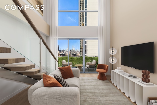 living area featuring a towering ceiling, wood finished floors, and stairs