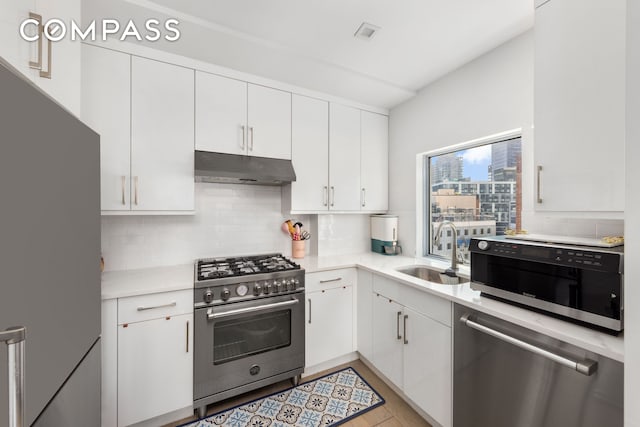 kitchen featuring tasteful backsplash, under cabinet range hood, stainless steel appliances, white cabinetry, and a sink