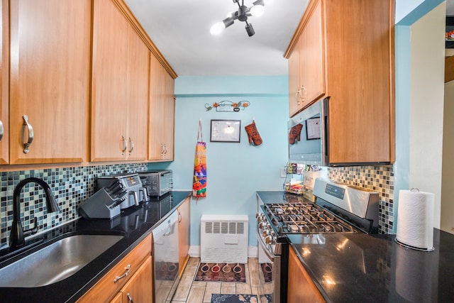 kitchen featuring backsplash, baseboards, dark stone countertops, stainless steel appliances, and a sink