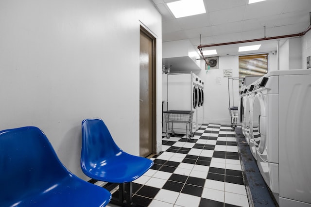 community laundry room featuring tile patterned floors and stacked washer / drying machine