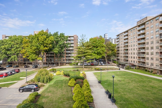 view of home's community with a yard, a view of city, and uncovered parking