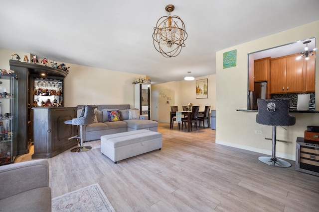 living area with a chandelier, light wood finished floors, and baseboards