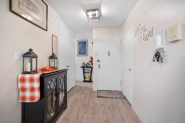 corridor with baseboards and light wood-style floors