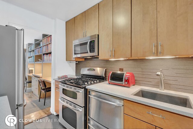 kitchen featuring appliances with stainless steel finishes, light stone counters, tasteful backsplash, and sink