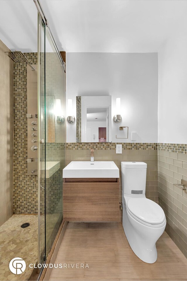 full bathroom featuring toilet, a stall shower, tile walls, and vanity