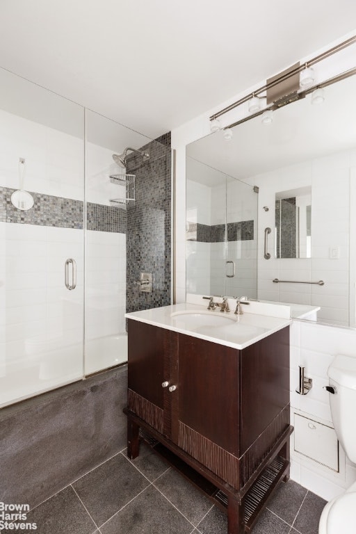 bathroom featuring vanity, toilet, tile walls, and walk in shower