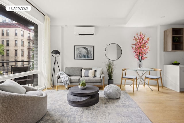 living room with an AC wall unit and light hardwood / wood-style floors