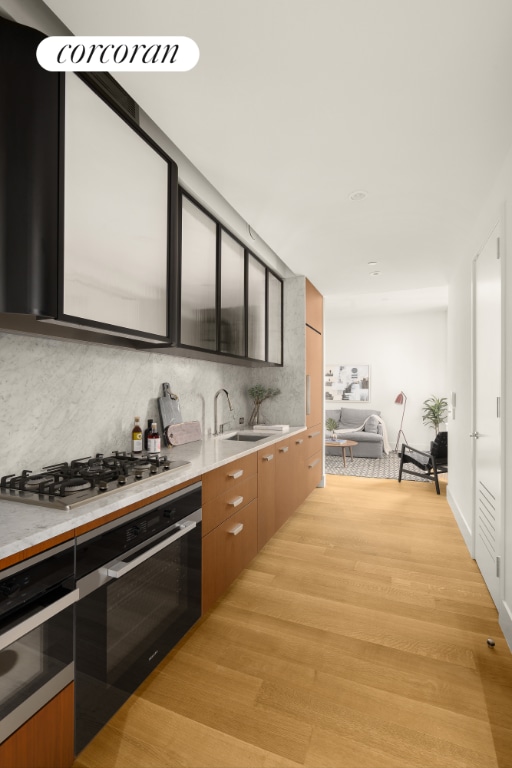 kitchen featuring tasteful backsplash, appliances with stainless steel finishes, sink, and light hardwood / wood-style flooring