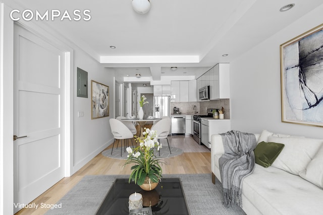 living area featuring baseboards, recessed lighting, and light wood-style floors