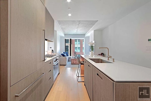 kitchen with a sink, open floor plan, light countertops, light wood-type flooring, and modern cabinets