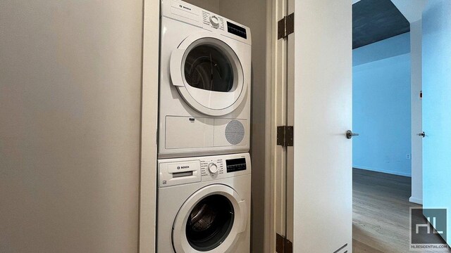 laundry room featuring stacked washer and dryer, laundry area, and wood finished floors