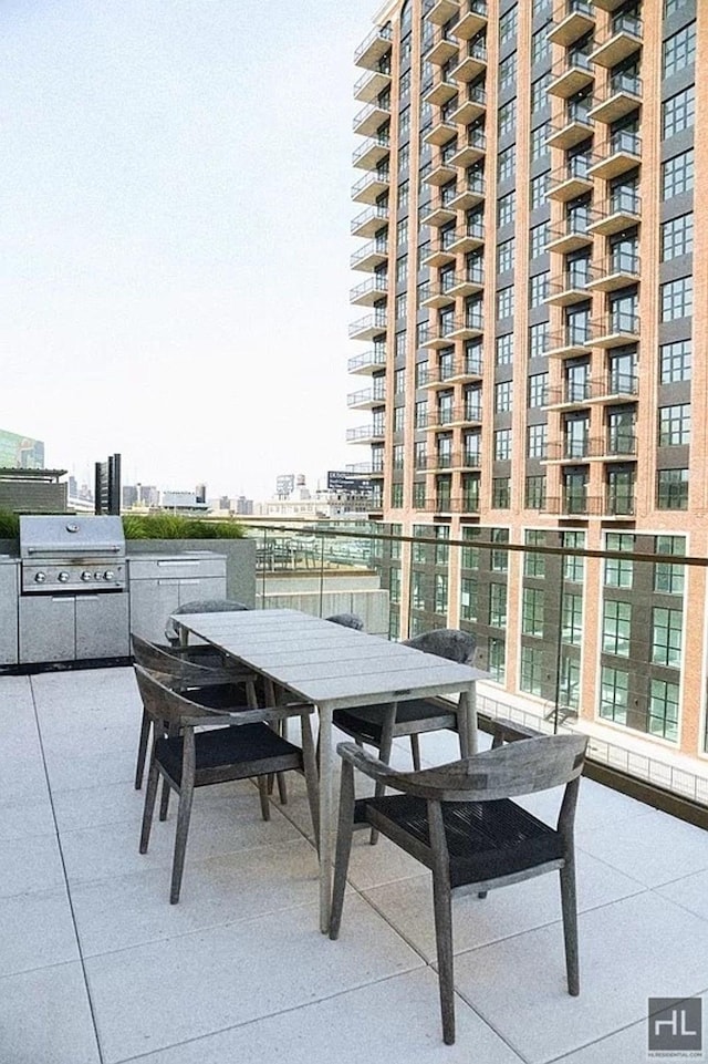 view of patio with grilling area, outdoor dining space, a view of city, and exterior kitchen