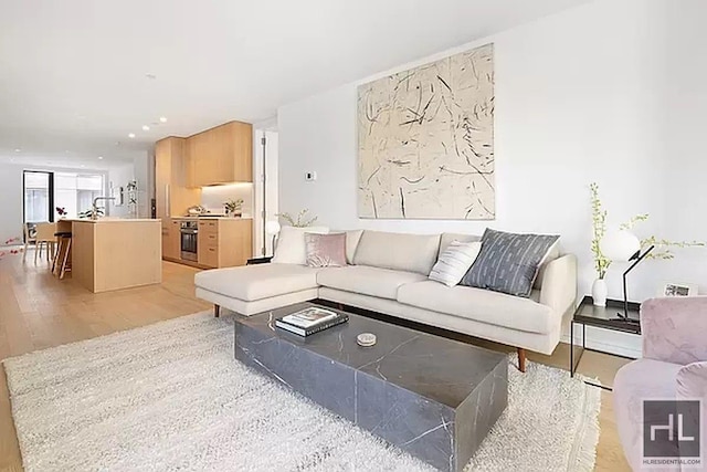 living area with light wood-type flooring and recessed lighting