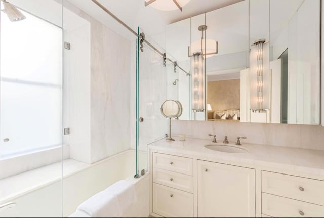 bathroom featuring combined bath / shower with glass door and vanity