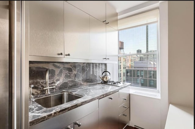 kitchen featuring decorative backsplash, dark stone countertops, and sink