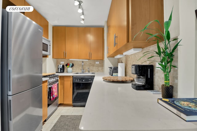 kitchen featuring rail lighting, sink, light tile patterned floors, stainless steel appliances, and backsplash