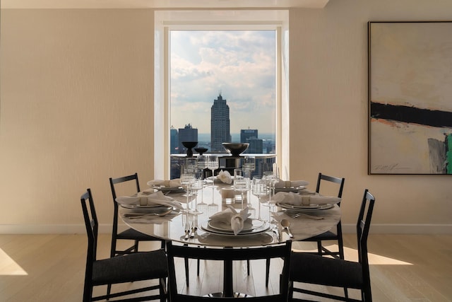 dining room with a city view, baseboards, and wood finished floors