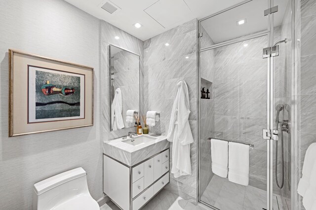 bathroom featuring toilet, vanity, a shower stall, and tile walls