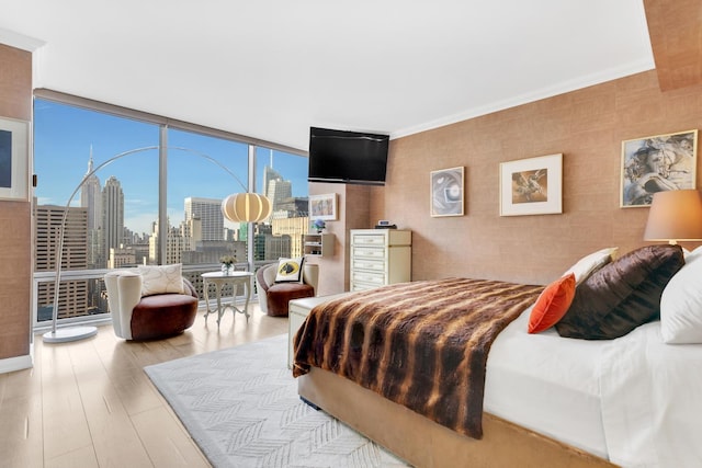 bedroom with light wood-style flooring, a wall of windows, and crown molding