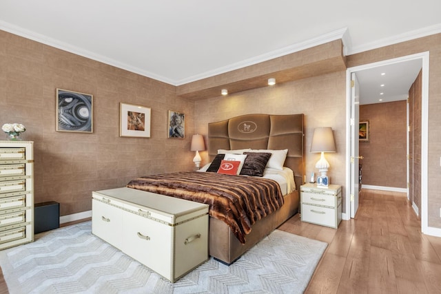 bedroom featuring ornamental molding, light wood-type flooring, and baseboards