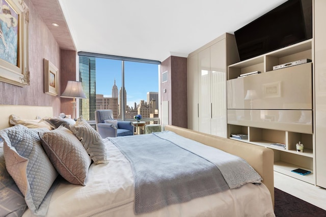 bedroom with a wall of windows, a view of city, and a closet