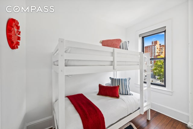 bedroom with baseboards and dark wood-type flooring