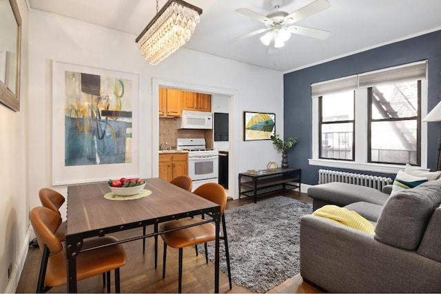 dining area with radiator, ceiling fan with notable chandelier, and light hardwood / wood-style flooring