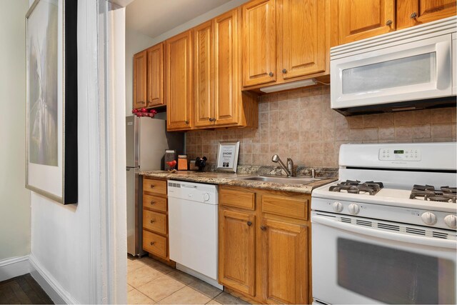 kitchen featuring tasteful backsplash, white appliances, light tile patterned flooring, and sink