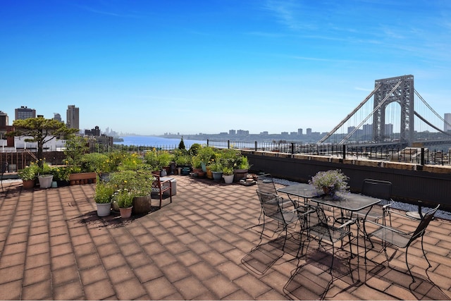 view of patio / terrace featuring a view of city, outdoor dining area, and a water view