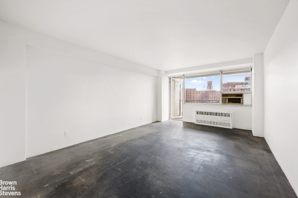 unfurnished room featuring a city view and radiator heating unit