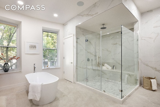 bathroom with a freestanding bath, a marble finish shower, and recessed lighting