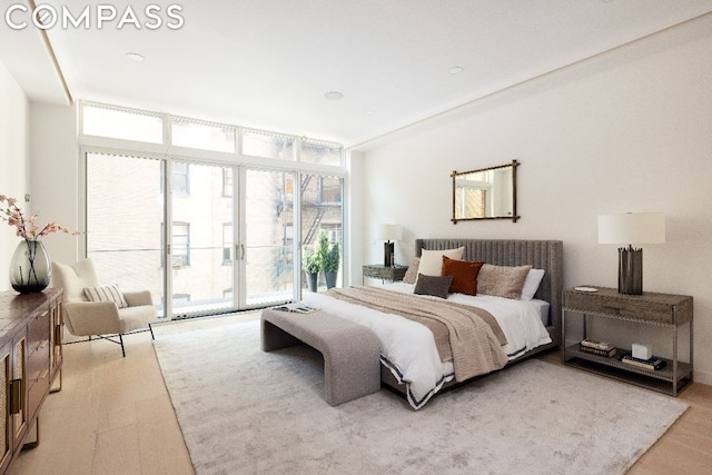 bedroom with access to outside, expansive windows, and light wood-type flooring