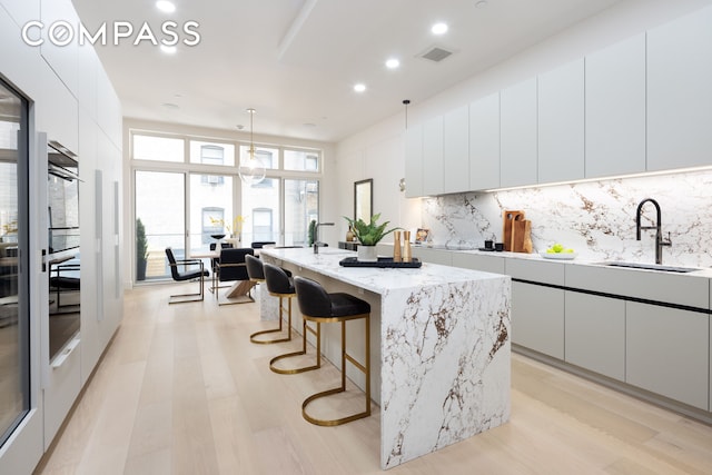 kitchen with visible vents, decorative backsplash, white cabinets, modern cabinets, and a sink