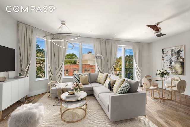 living room with an inviting chandelier, baseboards, and wood finished floors