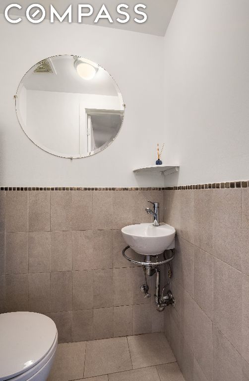 bathroom featuring tile walls, sink, tile patterned flooring, and toilet