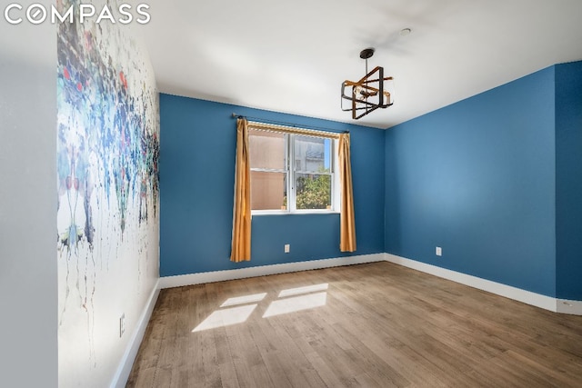 unfurnished room with a chandelier and hardwood / wood-style floors