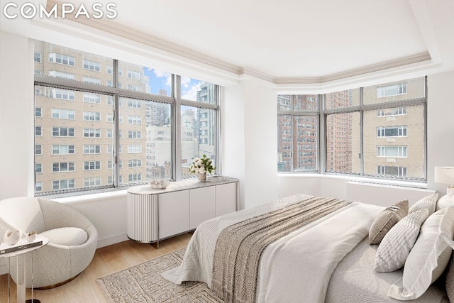 bedroom with ornamental molding, light hardwood / wood-style flooring, and multiple windows