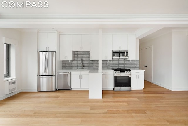 kitchen featuring white cabinetry, stainless steel appliances, decorative backsplash, light wood-type flooring, and sink