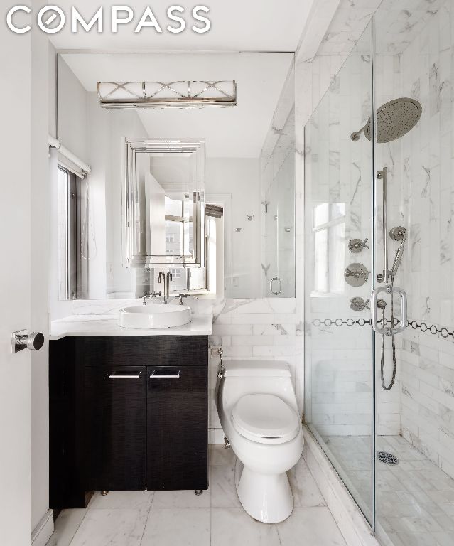 bathroom with toilet, an enclosed shower, and vanity