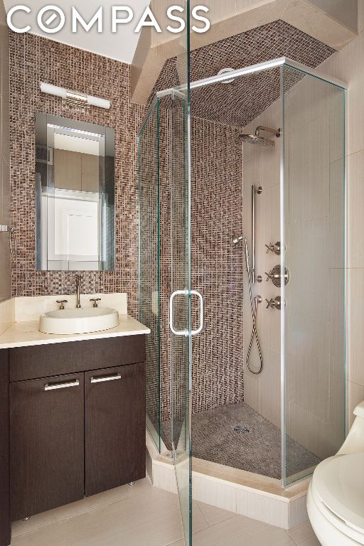 bathroom with vanity, toilet, tile patterned flooring, and an enclosed shower