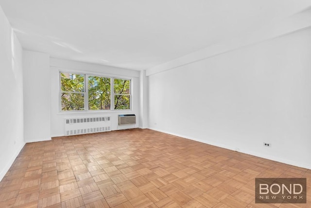 empty room with light parquet floors, radiator heating unit, and a wall unit AC