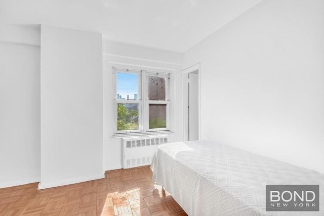 bedroom with light parquet floors and radiator heating unit