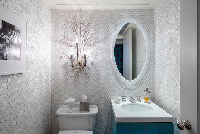 half bathroom featuring toilet, vanity, and ornamental molding