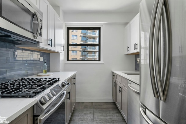 kitchen with sink, white cabinetry, appliances with stainless steel finishes, light stone countertops, and decorative backsplash