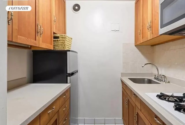 kitchen with tile patterned flooring, sink, decorative backsplash, and stainless steel appliances