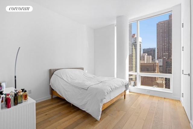 bedroom with wood-type flooring, visible vents, and a city view