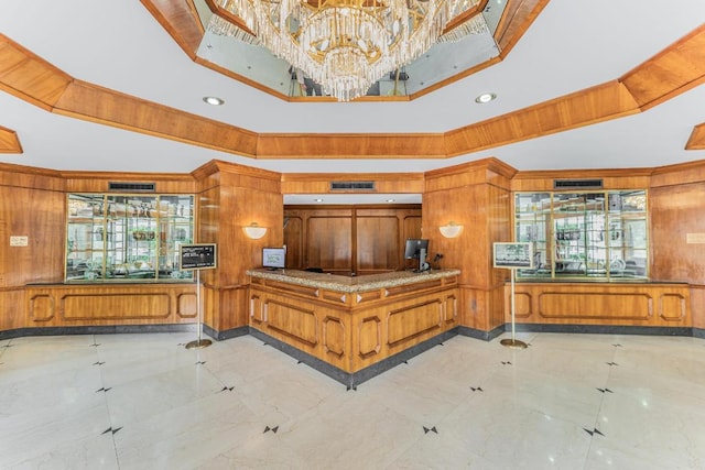 interior space featuring a tray ceiling, wooden walls, and an inviting chandelier